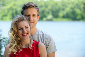 Obraz premium Young happy couple hugging and laughing on river background