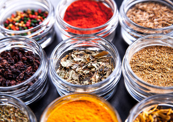 Spices on black background in special jars. Food