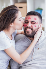 Obraz premium Woman kissing man with red lipstick all over his face,shallow depth of field