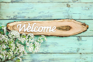 Welcome sign on cross cut tree branch with spring tree blossoms