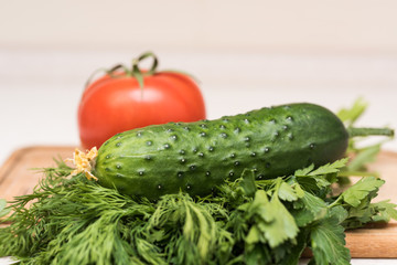 Fresh tomato, cucumber, parsley and dill on the cutting board