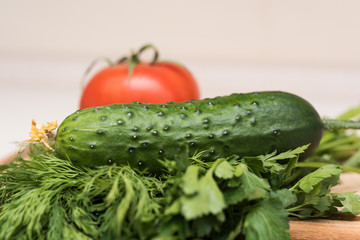 Fresh tomato, cucumber, parsley and dill on the cutting board