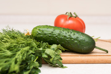Fresh tomato, cucumber, parsley and dill on the cutting board