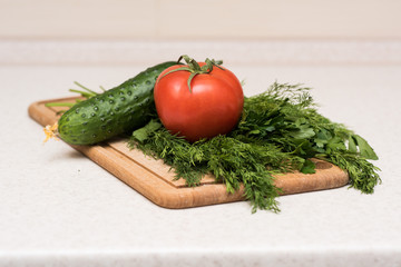 Fresh tomato, cucumber, parsley and dill on the cutting board