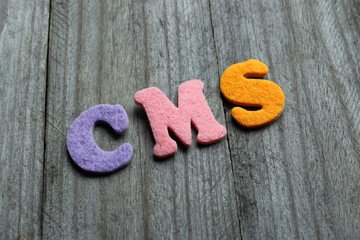 CMS (Content Management System) acronym on wooden background