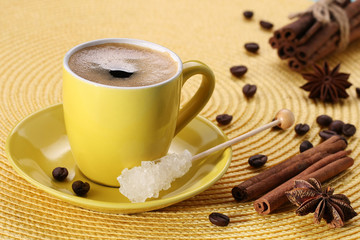 yellow cup with coffee, sugar, coffee beans, cinnamon, star anis