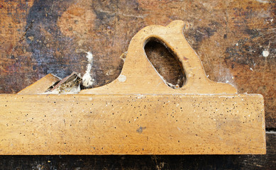 Old wooden plane on dirty table, struck by termites. Top view.