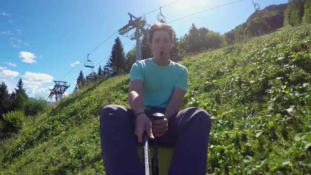 SELFIE: Cheerful young man riding summer sledge rollercoaster