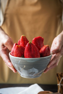 Person showing a bowl full of strawberries