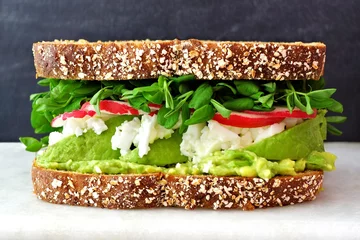 Zelfklevend Fotobehang Superfood sandwich met volkoren brood, avocado, eiwitten, radijs en erwtenscheuten op marmer tegen een zwarte achtergrond © Jenifoto