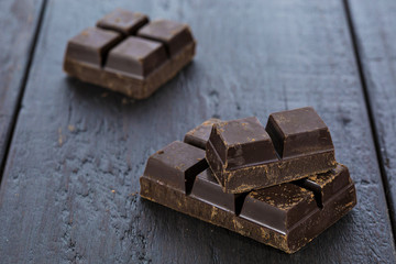 Dark chocolate pieces on wooden table background