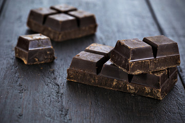 Dark chocolate pieces on wooden table background