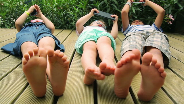 Baby foot close up. Children playing with electronic gadgets on the wooden floor