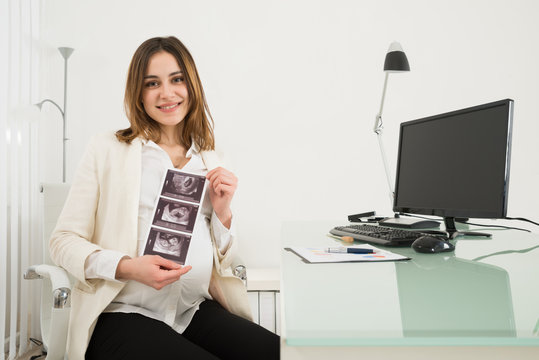 Pregnant Businesswoman Holding Ultrasound Scan Reports