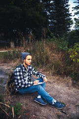 Young Man Traveler with backpack reading book and writing notes outdoor