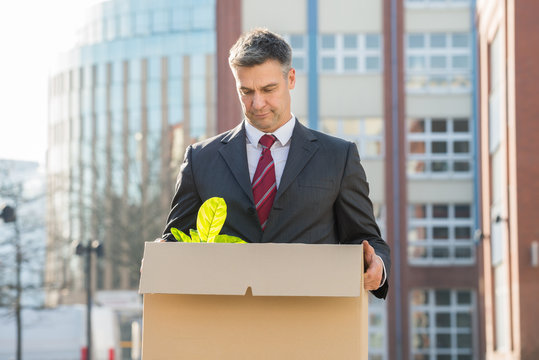 Businessman Standing With Cardboard Box Outside Office