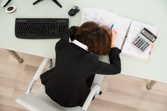 Businesswoman Sleeping With Invoices On Desk