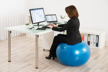 Businesswoman Sitting On Pilates Ball Working
