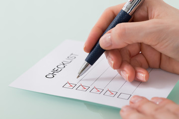 Woman Marking On Checklist Form With Red Pen