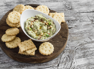 Healthy vegetarian broccoli and pine nuts hummus and homemade cheese biscuits on a wooden rustic board. Delicious snack or appetizer with wine