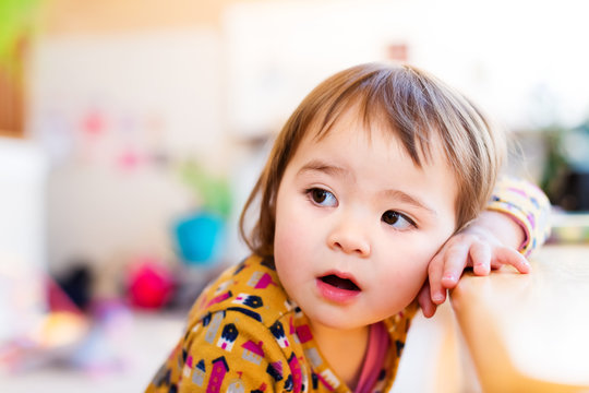 Toddler Girl Leaning Against Table