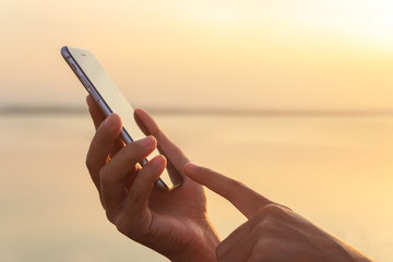 closeup hand using phone during at sunset
