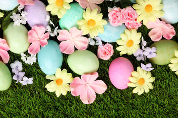 Colorful Easter eggs on grass with flowers background