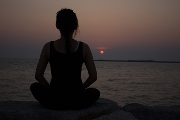 young woman doing yoga on coast of sea on beach