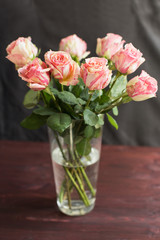 beautiful pink rose flowers in vase on wooden background