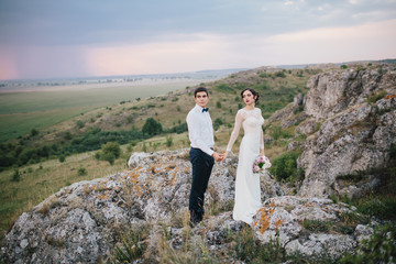 Beautiful wedding couple with bouquet flowers on the sunset