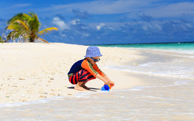 little boy playing with water on beach