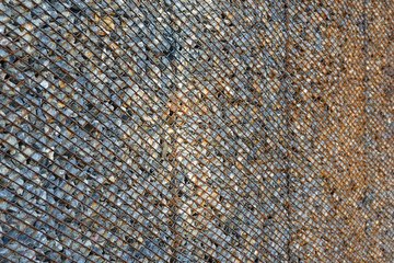 Background made from rusty metal mesh cage and stone