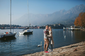 couple in love on the shore of a mountain lake Como with yachts