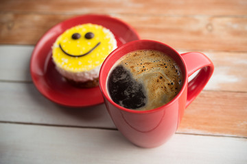 Coffee red cup and smile cake on wood table