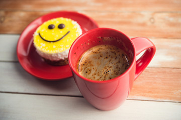 Coffee red cup and smile cake on wood table