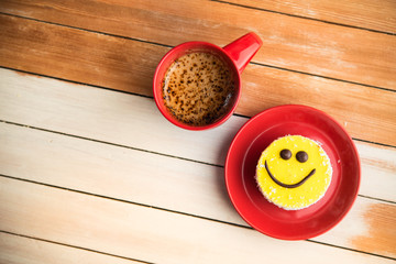 Coffee red cup and smile cake on wood table
