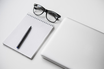 Laptop, black glasses, pen and notebook