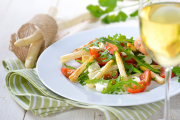 Gemischter Salat mit  gebratenem, weißen Spargel und Feta, serviert mit einem Glas trockenen...