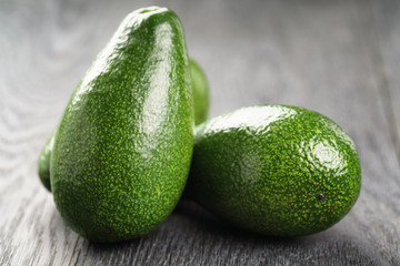 whole ripe green avocados on wood table, selective focus
