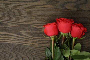 three red roses on wood table, directly above