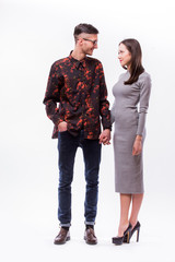 Happy hipster couple holding hands and look each other against white background