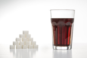 Glass full of soft drink with the amount of sugar / sweettner next to it