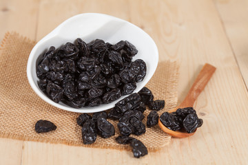 Raisin in the bowl on the wood background