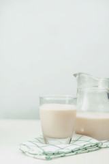 Milk in a glass jug and glass on wooden background