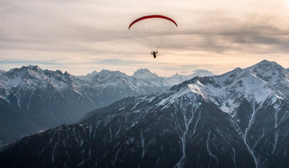 Paraglider flight over the snow-capped peaks of the Caucasus mountains