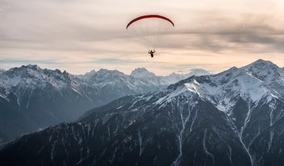 Fotobehang Luchtsport Paraglidervlucht over de met sneeuw bedekte toppen van de bergen van de Kaukasus