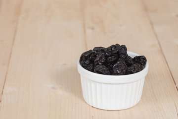 Raisin in the bowl on the wood background