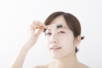 Fototapeta premium 女性 美容 アイブロウブラシ 道具 白バック カメラ目線