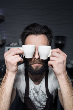 bartender keeps cups of coffee near face;