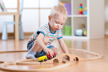 Child boy playing in his room with a toy train